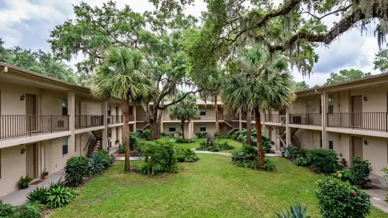 Two-story garden apartment complex with a courtyard and palm trees